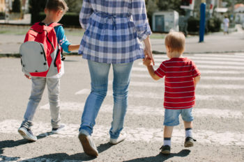 Walking to school. Mother with children crossing a road on way to school.